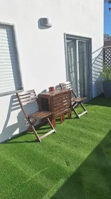 a patio with a table and chairs on the grass at Casa Rafinha in Faro