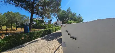 a white wall next to a sidewalk with trees at Quinta do Lagar - 10 in Albufeira