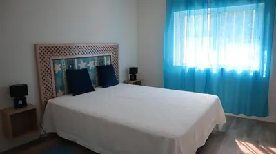 a bedroom with a large white bed with blue curtains at MFA By Albufeira Rental in Albufeira