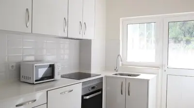 a white kitchen with a microwave and a sink at MFA By Albufeira Rental in Albufeira