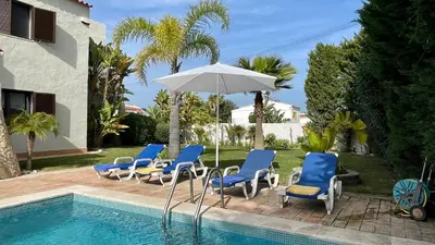 a group of chairs and an umbrella next to a swimming pool at Golfinho by Check-in Portugal in Albufeira