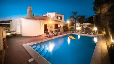 a swimming pool in front of a house at night at Golfinho by Check-in Portugal in Albufeira