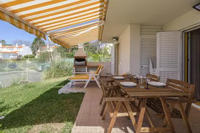 a patio with wooden tables and chairs and a grill at The Albufeira Concierge - Villa Pool & Tennis in Albufeira