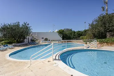 a large swimming pool with a metal railing around it at The Albufeira Concierge - Villa Pool & Tennis in Albufeira
