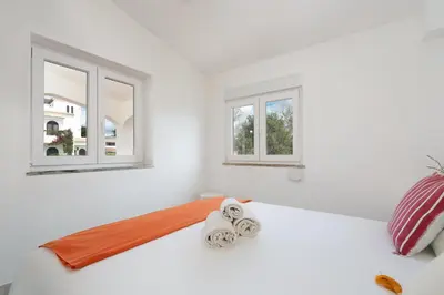 a bedroom with a white bed with two windows at Sunny Albufeira - 5min to the beach by LovelyStay in Albufeira