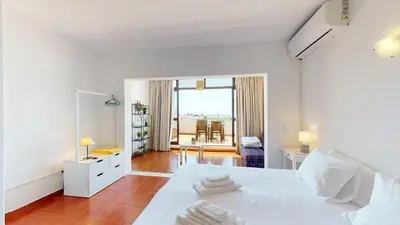 a white bedroom with a white bed and a desk at Apartamento CPiscina-Albufeira in Albufeira
