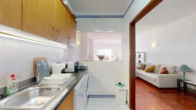 a kitchen with a sink and a couch in a room at Apartamento CPiscina-Albufeira in Albufeira