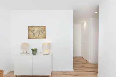 a room with white walls and a table with a lamp at New 2bedroom Apartment w Terrace & Infinity Pool in Olhos de Água