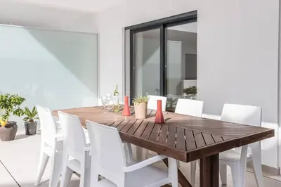 a dining room with a wooden table and white chairs at New 2bedroom Apartment w Terrace & Infinity Pool in Olhos de Água