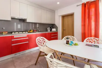 a kitchen with red cabinets and a white table and chairs at Villa Petala in Albufeira