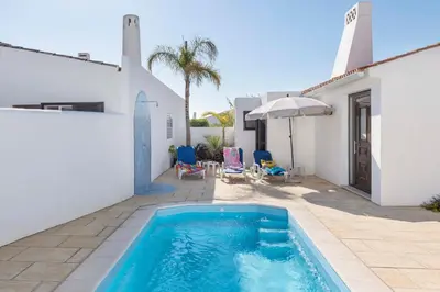a swimming pool in front of a white house at Villa Petala in Albufeira