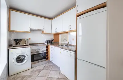 a kitchen with white cabinets and a washer and dryer at LongLands Peak at Windmill Hill in Albufeira