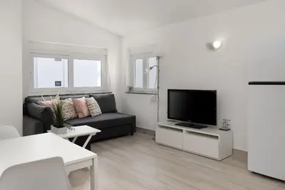 a living room with a black couch and a flat screen tv at Bright Albufeira - 5min to the beach by LovelyStay in Albufeira