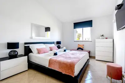a bedroom with a large bed with pink pillows at Villa PACA Algarve Vilamoura 8 personnes in Quarteira