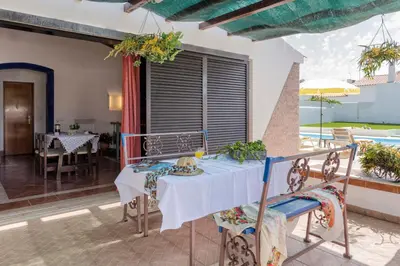 a dining room with a table and a pool at Villa Jacaranda in Albufeira