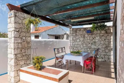 a patio with a table and chairs and a stone wall at Villa Jacaranda in Albufeira