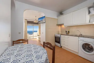 a kitchen with a table and a washing machine at Oceanview Apartment A by Sequeira in Albufeira