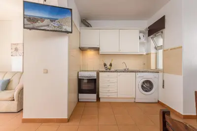 a kitchen with white cabinets and a washer and dryer at Oceanview Apartment A by Sequeira in Albufeira