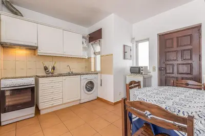 a kitchen with white cabinets and a bed in a room at Oceanview Apartment A by Sequeira in Albufeira