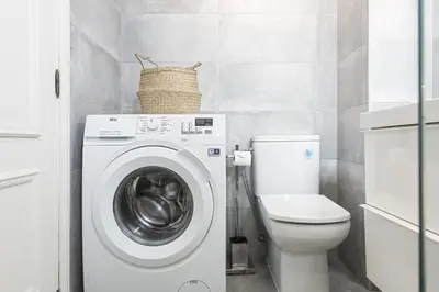 a bathroom with a washing machine and a toilet at Scandic - City Center by HD Properties in Vilamoura
