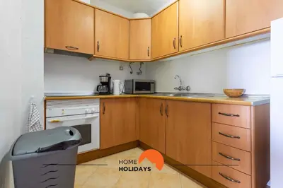 a kitchen with wooden cabinets and a trash can at #114 T2 Foxy H by Home Holidays in Albufeira