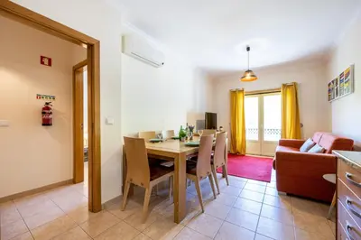 a dining room and living room with a table and chairs at Jacaranda in Albufeira