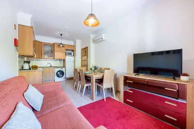 a living room with a couch and a dining room at Jacaranda in Albufeira