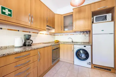 a kitchen with wooden cabinets and a washer and dryer at Jacaranda in Albufeira