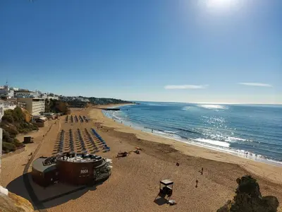a beach with a bunch of chairs and the ocean at Candyland Apartment in Albufeira