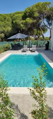 a blue swimming pool with chairs and an umbrella at Valverde 2 Villa, Vilamoura, Algarve, only 5 minutes from Marina, Golf and Beach in Vilamoura