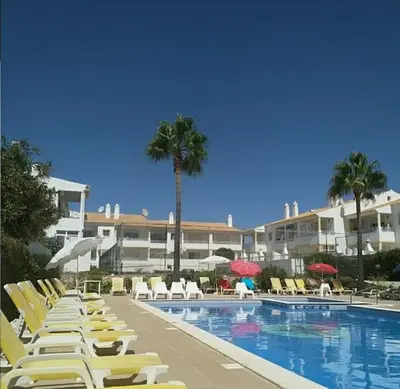 a swimming pool with yellow lounge chairs and palm trees at Superior Apartment Casa Vela Albufeira S Rafael beach in Albufeira