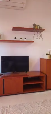 a flat screen tv sitting on top of a wooden entertainment center at Appart Oura Strip in Albufeira
