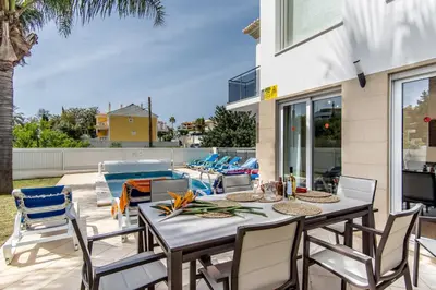 a patio with a table and chairs next to a pool at Villa Casa Vilas Boas in Albufeira