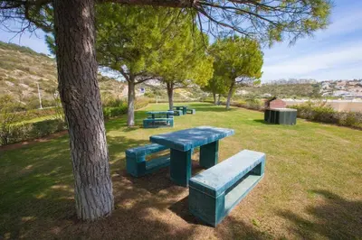 a group of picnic tables in a park next to a tree at Jardins da Marina Albufeira in Albufeira