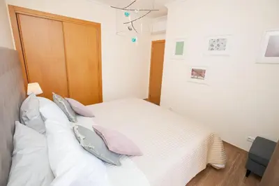 a bedroom with a white bed with pillows on it at Jardins da Marina Albufeira in Albufeira