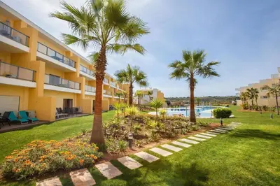 a resort yard with palm trees and a swimming pool at Jardins da Marina Albufeira in Albufeira