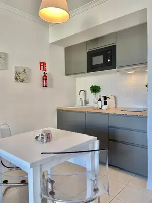 a kitchen with a white table and a microwave at F&V Studio Vilamoura in Quarteira