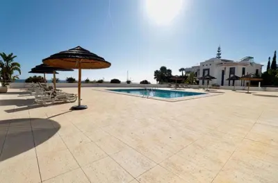 a patio with an umbrella and a swimming pool at Apartamento Varandas do Mar in Albufeira