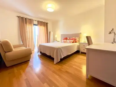 a bedroom with a bed and a chair and a window at Vivenda em Vilamoura Marina Ténis Academy in Vilamoura