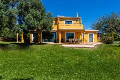 a yellow house with a lawn in front of it at Vila Limão in Boliqueime