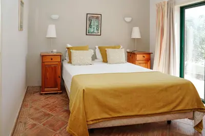 a bedroom with a bed with a yellow blanket on it at Vila Limão in Boliqueime