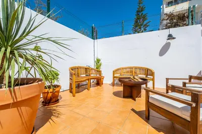 a patio with wooden benches and potted plants at Stunning terrace with ocean view in Albufeira