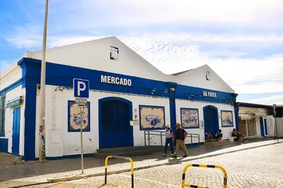 two people walking in front of a blue and white building at Coluna Mar in Quarteira