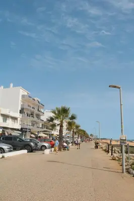 a sidewalk next to the beach with cars parked at Coluna Mar in Quarteira