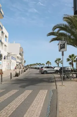 a street with cars parked on the side of the road at Coluna Mar in Quarteira