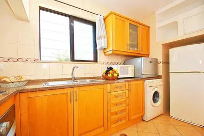 a kitchen with wooden cabinets and a white refrigerator at Villa Isis by Algarve Vacation in Albufeira