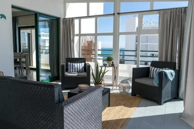 a living room with two chairs and a large window at Ocean Blue in Quarteira