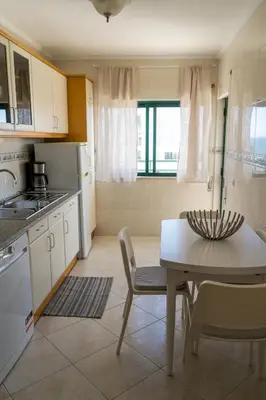 a kitchen with a table and chairs in a kitchen at Ocean Blue in Quarteira