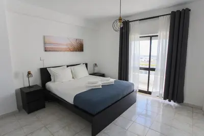 a bedroom with a bed and a large window at Go4Portugal - Dinis - Luxe Condo with Pool, Airco, Seaview with two Balcony in Albufeira