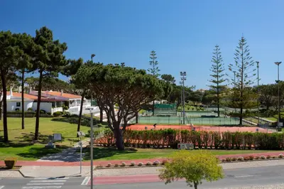 a park with two tennis courts and a tree at Vila Senna in Vale do Lobo